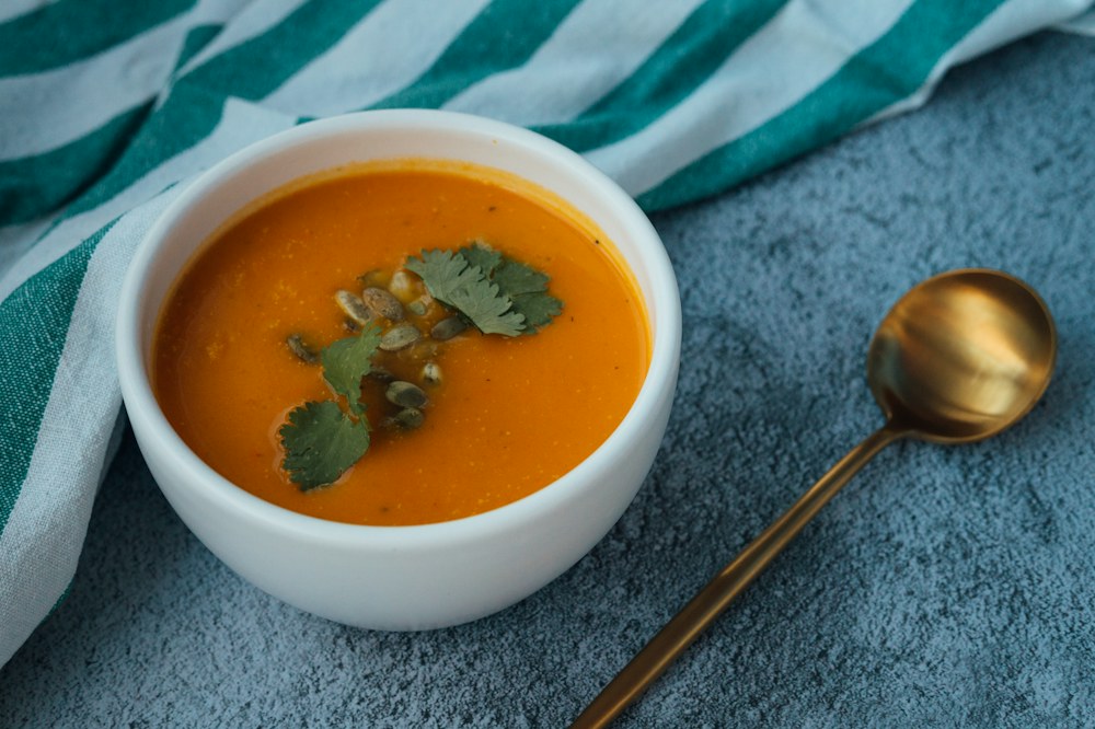 Un bol de soupe orange avec quelques graines